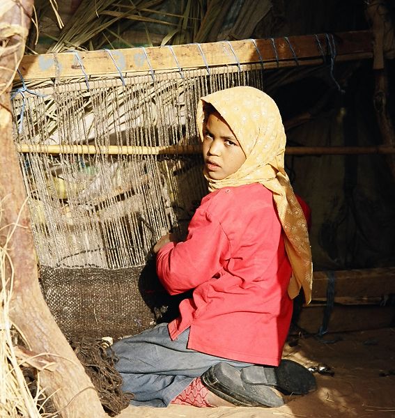 Little girl weaving a carpet, Sahara desert